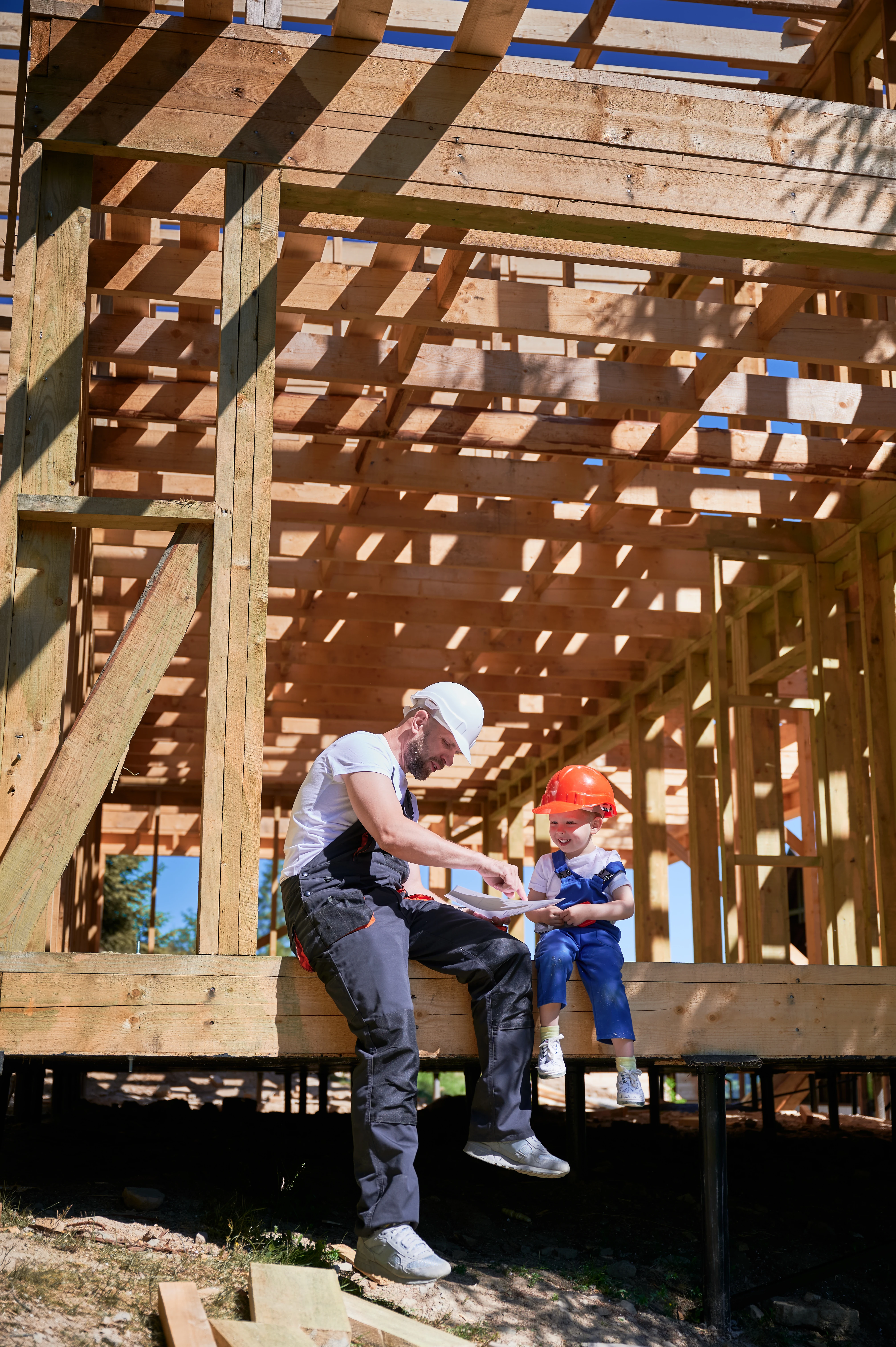 un père montre à son fils des plans de construction ossature bois